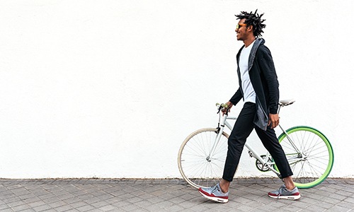 Man walking down a sidewalk with his green bike.