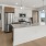 Spacious and well lit kitchen with wood floors and stainless steel appliances. 
